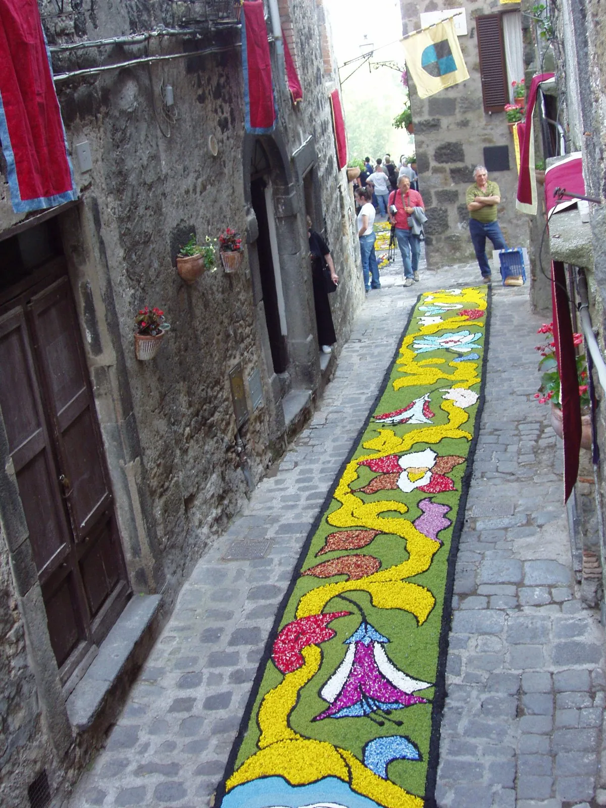 Un tappeto di petali colorati con motivi floreali steso lungo un vicolo in pietra del centro storico di Bolsena per il Corpus Domini